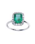 Emerald-cut Muzo emerald ring with halo diamonds in 14K white gold.