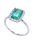 A semi-lateral view of a natural colombian emerald into a halo diamond in 14k white gold ring.
