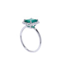 Emerald and diamond ring in white gold side profile view.