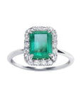 A rectangular emerald-cut encircled by a halo natural diamond emerald ring in 14k white gold.