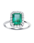 A rectangular emerald-cut encircled by a halo natural diamond emerald ring in 14k white gold.