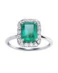 A rectangular emerald-cut encircled by a halo natural diamond emerald ring in 14k white gold.