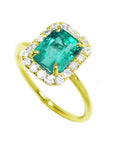 This emerald ring on a tilted position is displaying the top emerald, halo diamond and band of the ring.