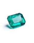 Vibrant bluish-green emerald-cut loose emerald from Muzo Colombia, 4.18 carats, on a white background.
