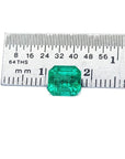 1.55 carat emerald-cut Muzo Colombian loose emerald, sparkling medium bluish green, next to a ruler.