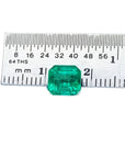 1.55 carat emerald-cut Muzo Colombian loose emerald, sparkling medium bluish green, next to a ruler.