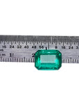 Vibrant bluish-green 4.18 carat emerald-cut loose emerald from Muzo, Colombia, next to a ruler.