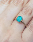 Emerald-cut Muzo Colombian emerald ring with a medium bluish-green gemstone set in a gold band on a hand.