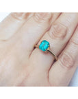 Emerald-cut Muzo Colombian emerald ring with a medium bluish-green gemstone set in a gold band on a hand.