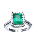Emerald-cut Muzo Colombian emerald ring with diamond halo and pavé band.