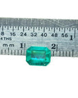 1.57 carat emerald-cut Muzo Colombian emerald, sparkling medium bluish green, next to a ruler.