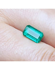 2.55-carat emerald-cut natural Colombian emerald with a medium deep green hue, held in a hand.