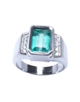 Men's 18K white gold ring with a bezel-set emerald-cut bluish-green emerald and side diamonds.