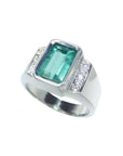 Men's 18K white gold ring with a bezel-set emerald-cut bluish-green emerald and diamond accents.