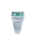 Men's 18K white gold ring with a bezel-set emerald-cut bluish-green emerald and diamond accents.