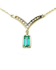 14K yellow gold necklace with a baguette-cut Colombian emerald and diamond-studded V-shaped pendant.