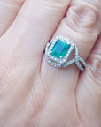 Ring with a real colombian emerald and accent diamonds on a hand against a natural background.