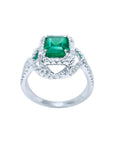 Emerald-cut Colombian emerald ring with halo diamonds in 18K white gold.