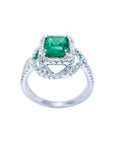 Emerald-cut Colombian emerald ring with halo diamonds in 18K white gold.