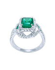 Emerald-cut Colombian emerald ring with halo diamonds in 18K white gold.