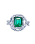 An emerald-cut natural colombian emerald in a halo diamond ring for ladies made of 18k white gold.