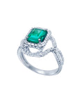 Emerald-cut natural emerald ring with halo diamonds and intertwined 18K white gold band.