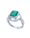 Emerald-cut natural emerald ring with halo diamonds and intertwined 18K white gold band.