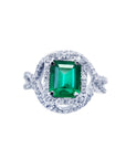 An emerald-cut natural colombian emerald in a halo diamond ring for ladies made of 18k white gold.