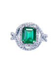 An emerald-cut natural colombian emerald in a halo diamond ring for ladies made of 18k white gold.