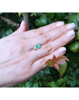 Emerald-cut natural emerald stud earrings, 1.29 ct, set in 14K yellow gold on a hand.
