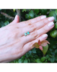 Emerald-cut natural emerald stud earrings, 1.29 ct, set in 14K yellow gold on a hand.