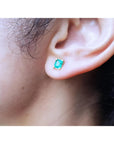 Emerald-cut natural emerald stud earring in 14K yellow gold, worn on an ear.