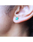 Emerald-cut natural emerald stud earring in 14K yellow gold, worn on an ear.