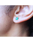 Emerald-cut natural emerald stud earring in 14K yellow gold, worn on an ear.