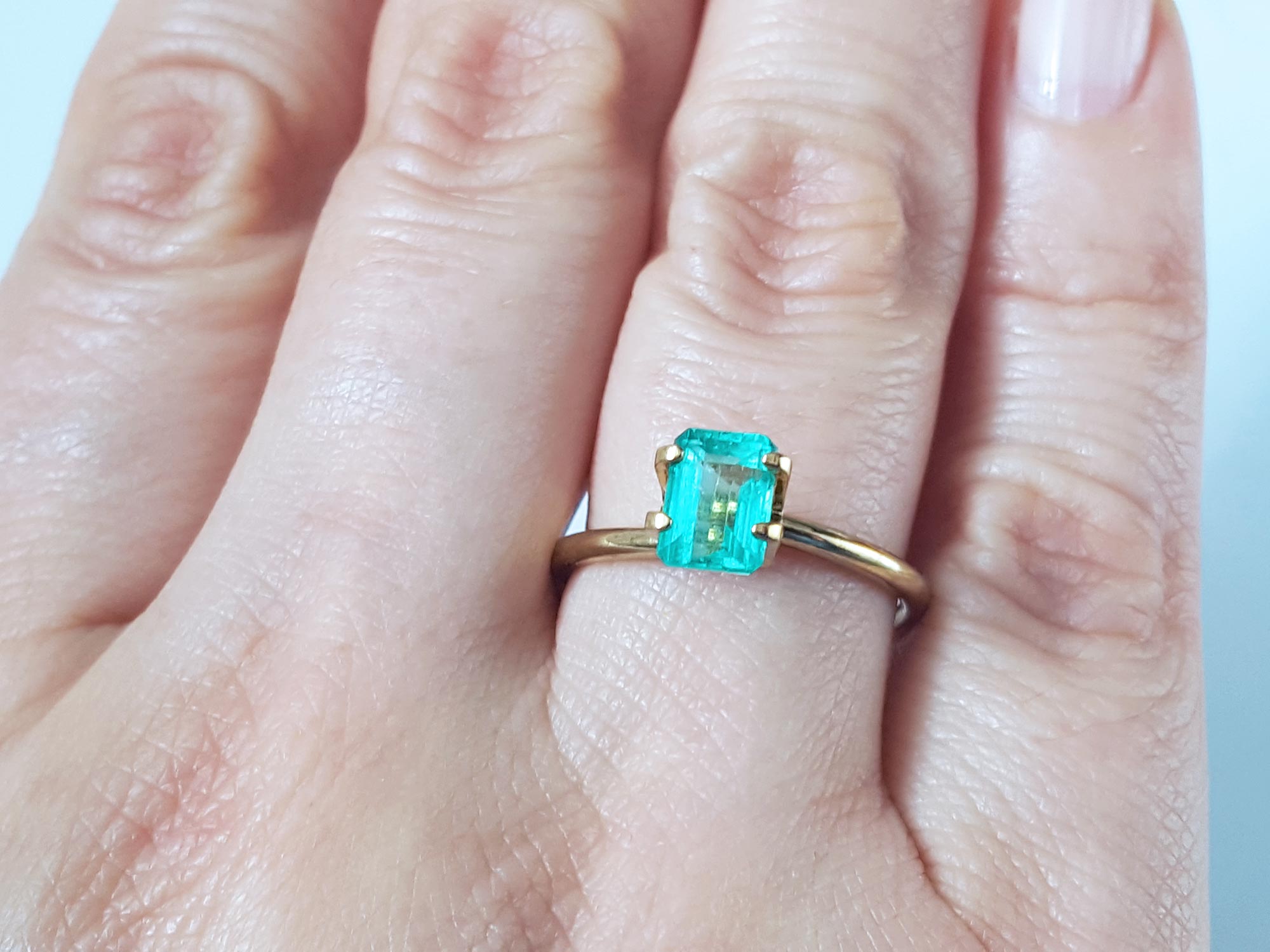 Affordable emerald-cut loose Colombian emerald on a woman's hand