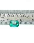1.13 carat emerald-cut Muzo Colombian emerald, a rectangular green gemstone shown against a ruler.