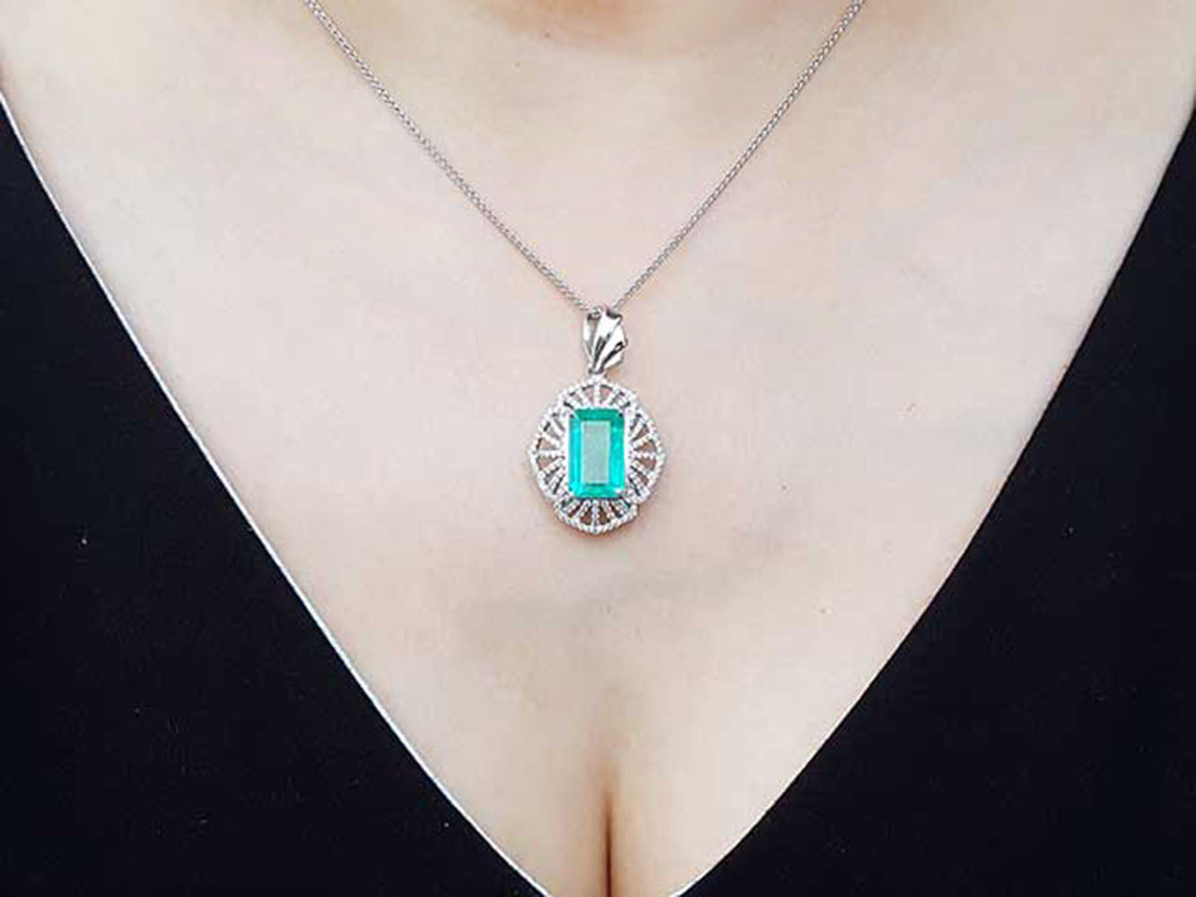 A natural colombian emerald pendant on a person's neck.