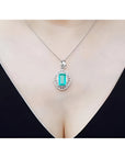 Emerald-cut emerald pendant with natural diamonds on a 14K white gold chain, worn on a woman's neck.