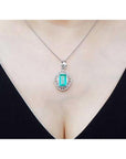 Emerald-cut emerald pendant with natural diamonds on a 14K white gold chain, worn on a woman's neck.