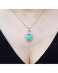 Emerald-cut emerald pendant with natural diamonds on a 14K white gold chain, worn on a woman's neck.