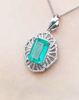 Emerald pendant necklace on a person's neck against a neutral background