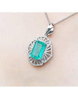 Emerald pendant necklace on a person's neck against a neutral background