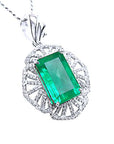 A natural colombian emerald-cut emerald pendant with diamond accents on a white gold design.