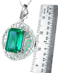 Emerald green gemstone pendant with white gold chain, next to a ruler for scale.