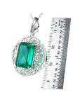 Emerald green gemstone pendant with white gold chain, next to a ruler for scale.