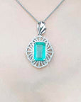 A rectangular natural emerald pendant in white gold and accent diamonds on topside view.