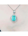 A rectangular natural emerald pendant in white gold and accent diamonds on topside view.