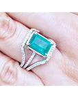 Emerald-cut 3.90 ct bluish-green emerald ring with triple diamond rows on 14K white gold.