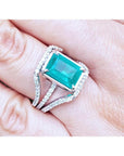 Emerald-cut 3.90 ct bluish-green emerald ring with triple diamond rows on 14K white gold.