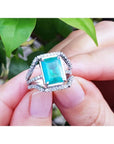 Emerald-cut 3.90 ct natural emerald ring with triple diamond rows in 14K white gold, held by hands.